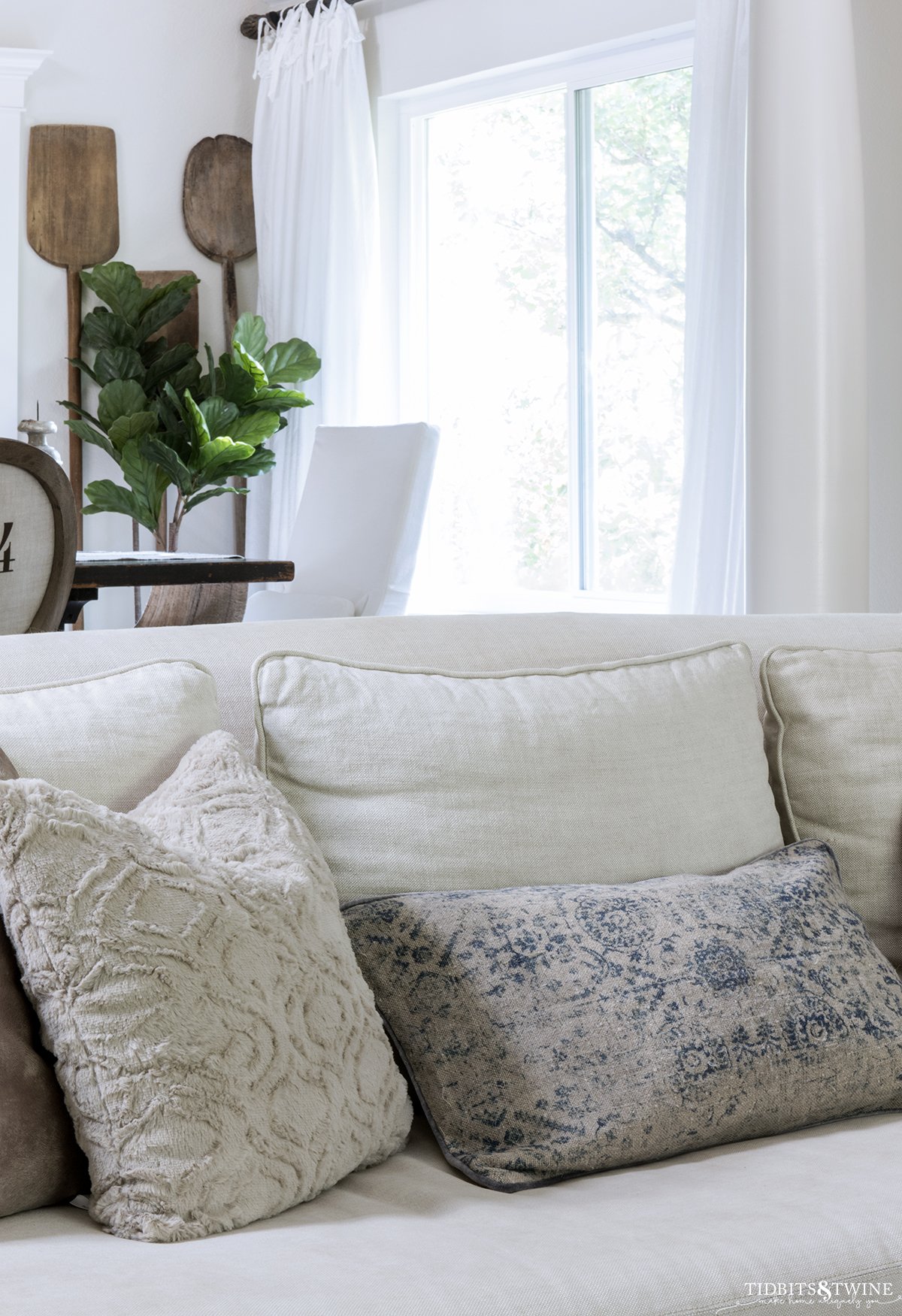 beige linen slipcovered sofa with throw pillows in beige faux fur and vintage lumbar pillow