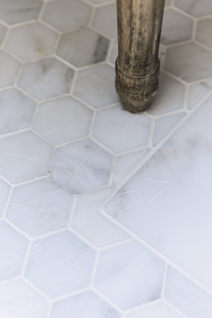 closeup of two inch hex marble tile floor in bathroom showing scratches from a chair leg