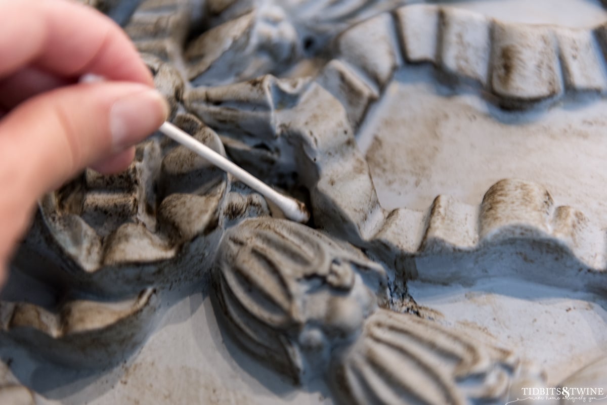 closeup showing application of dark wax on french mirror using a q-tip