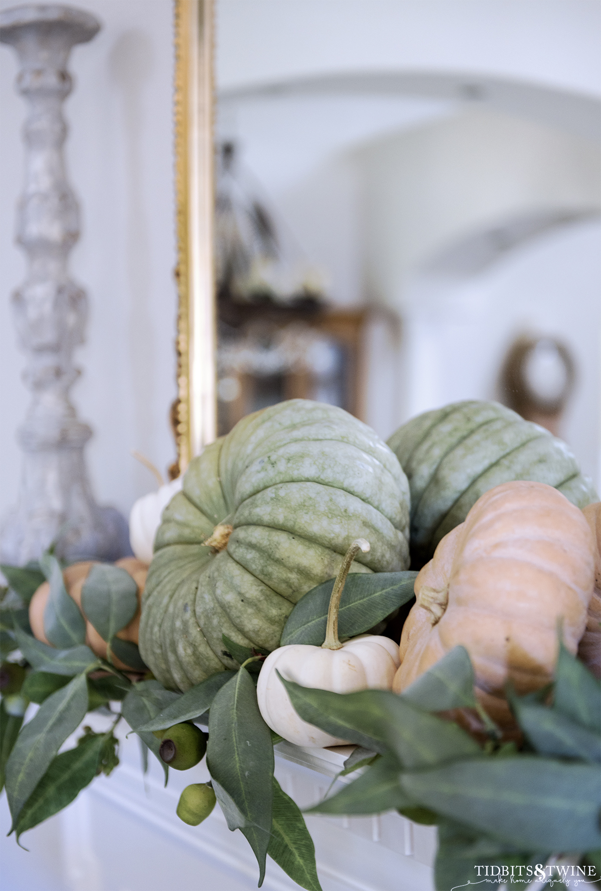 closeup of green white and terracotta pumpkins on fireplace mantel with eucalyptus gold mirror and candlestick