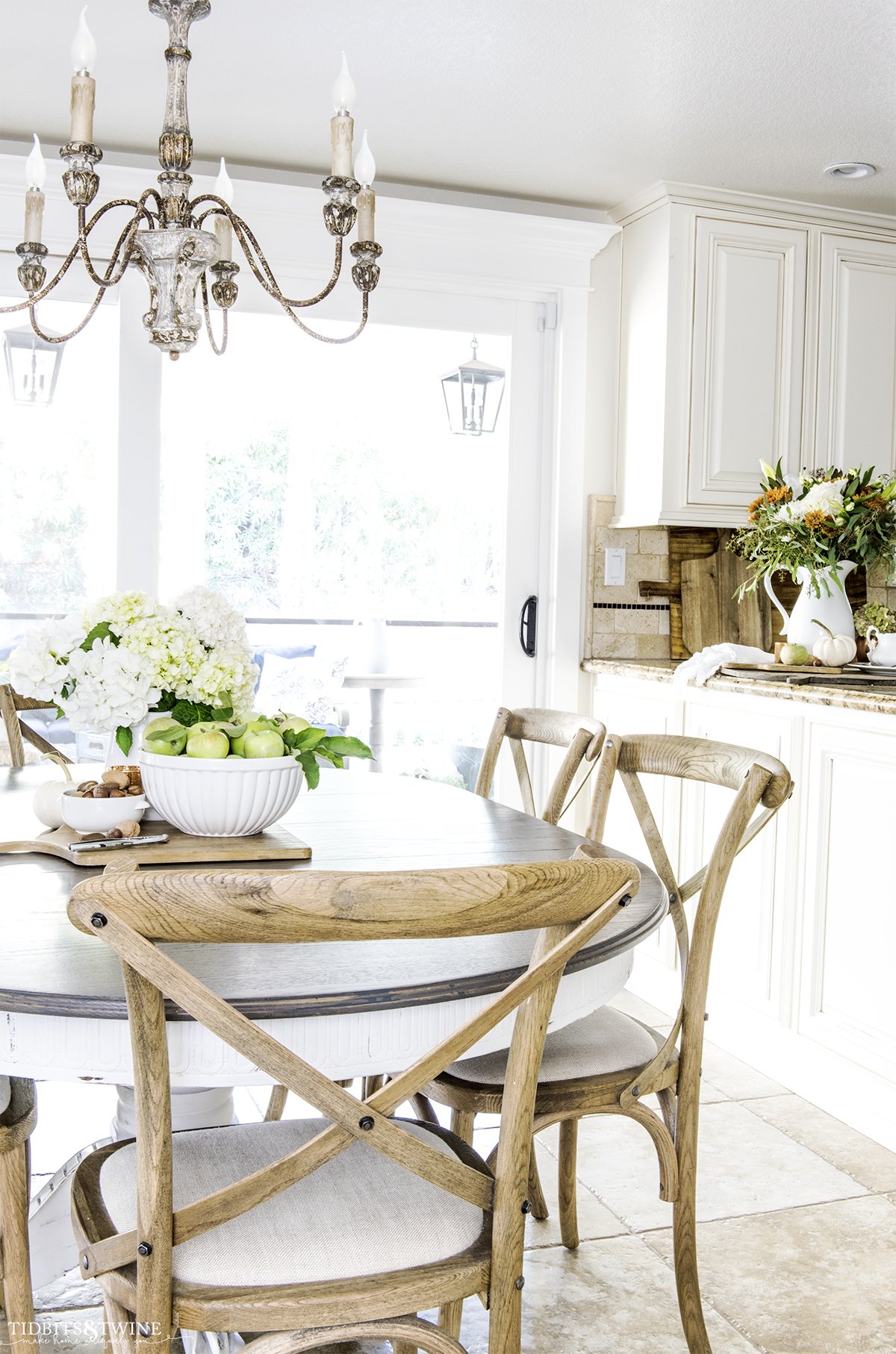 kitchen with white cabinets and granite counter with farmhouse table decorated for fall with apples hydrangea and copper accents