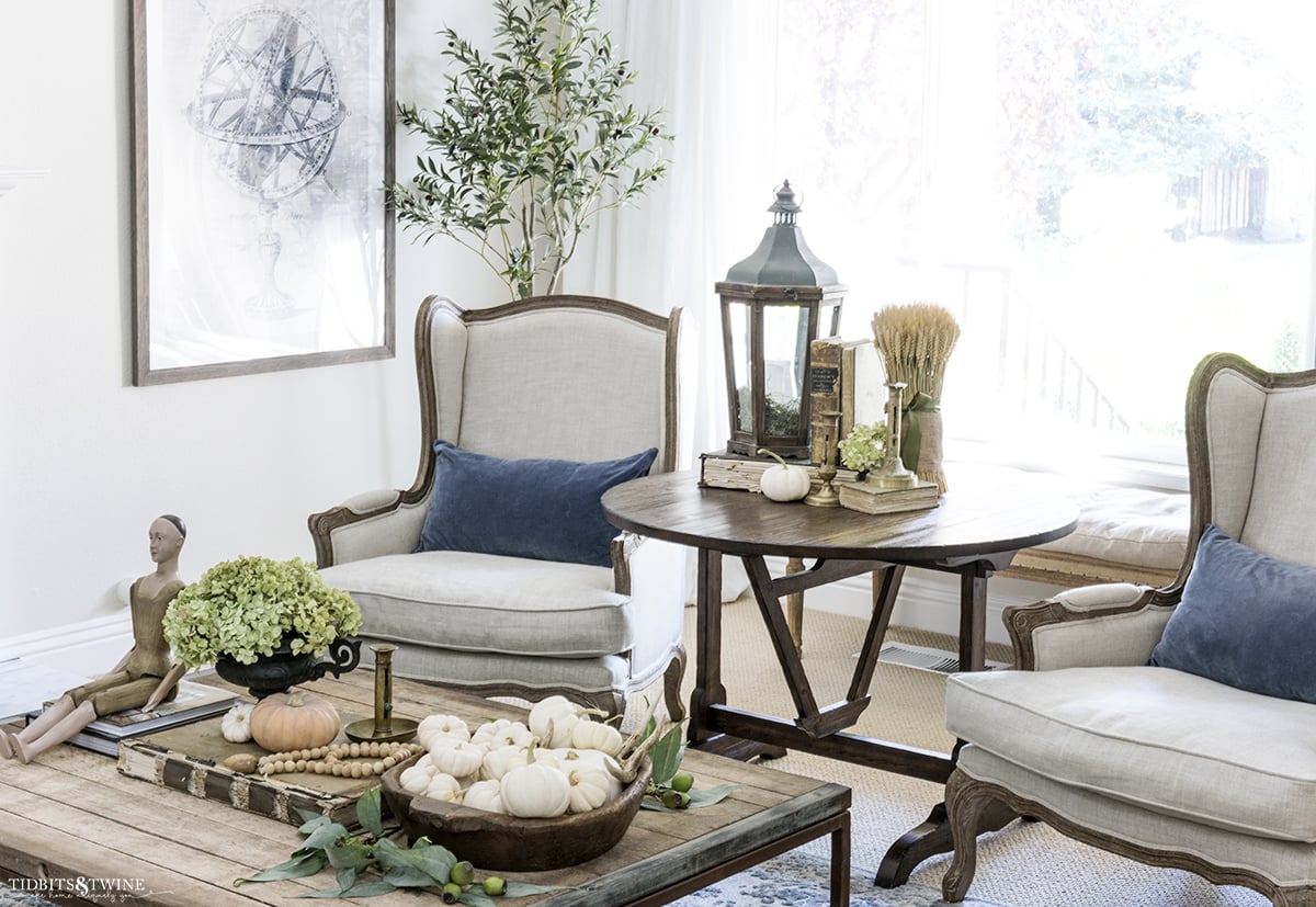 french living room with fireplace decorated for fall and linen wingback chairs