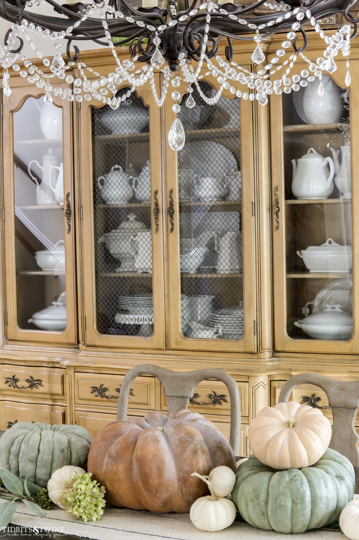 orange green and white pumpkins for fall on dining table with french cabinet against wall full of white ironstone collection