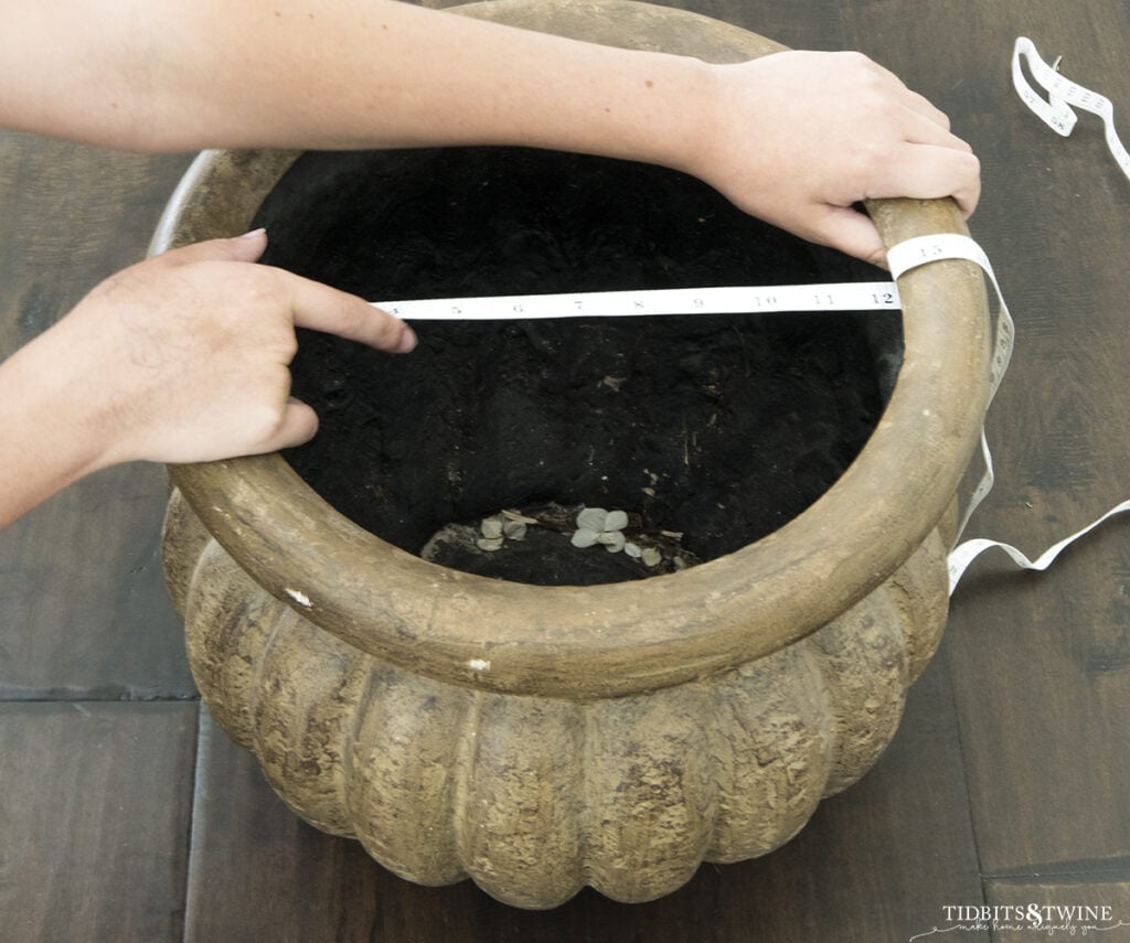 tape measuring the opening of a brown plastic pot