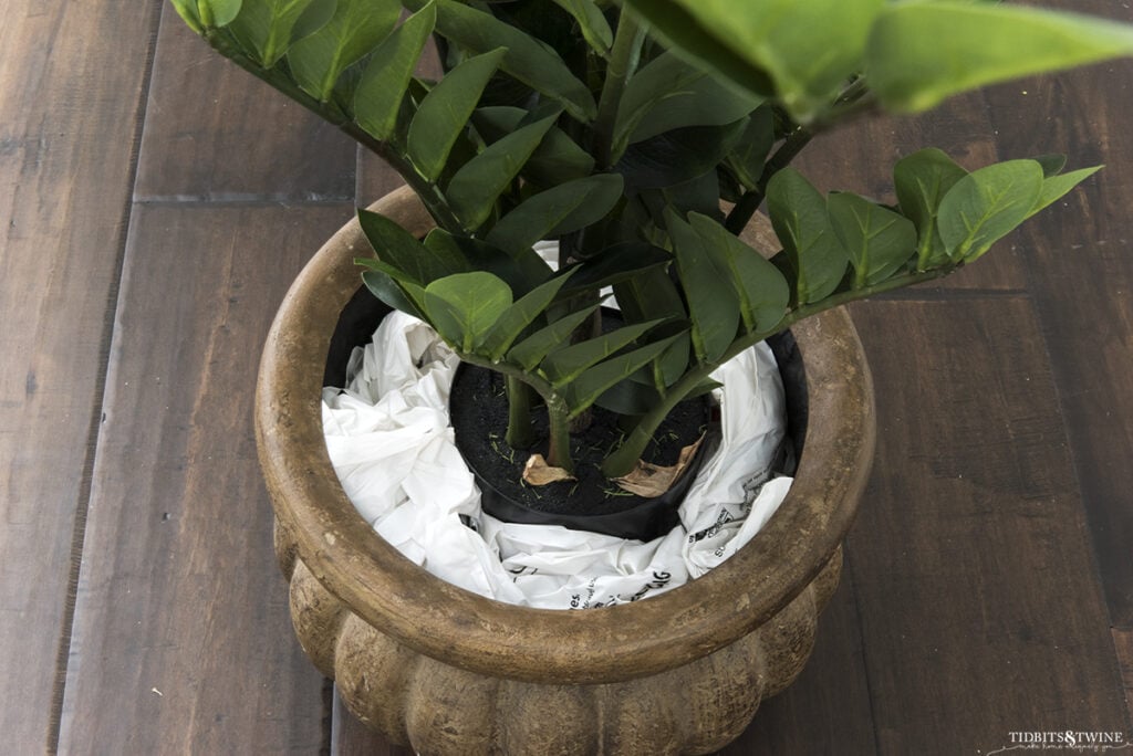 artificial zz plant in brown pot surrounded by stuffed grocery bags