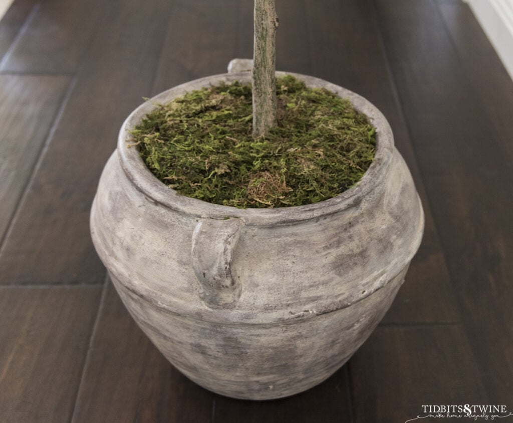 brown clay pot with artificial plant topped with moss to look real