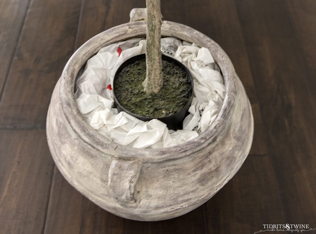 brown clay pot with artificial plant surrounded by stuffed grocery bags