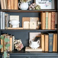 Black vintage cabinet decoratively styled with antique books dried hydrangea and ironstone