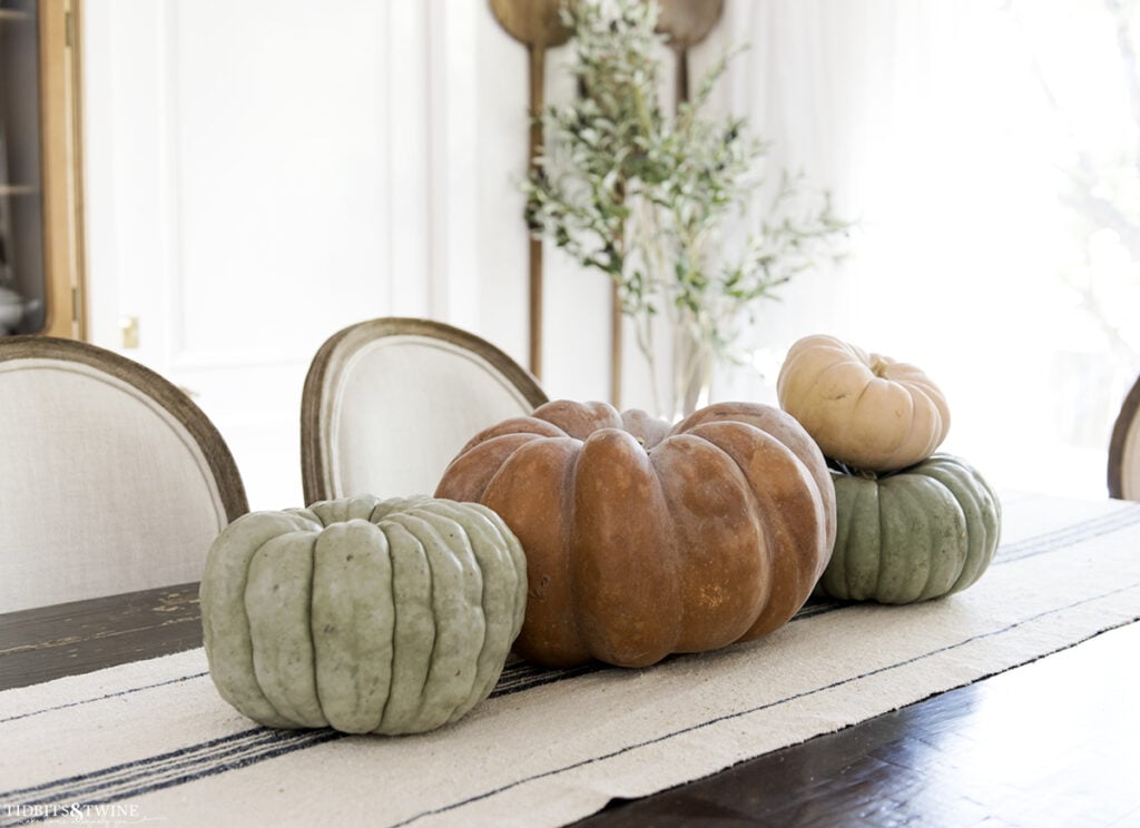 French dining room with terracotta pumpkin on center of table and smaller green ones on either side