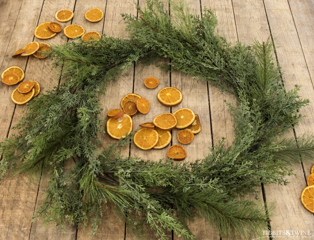 Christmas greenery wired to a wreath frame with dried orange slices surrounding it