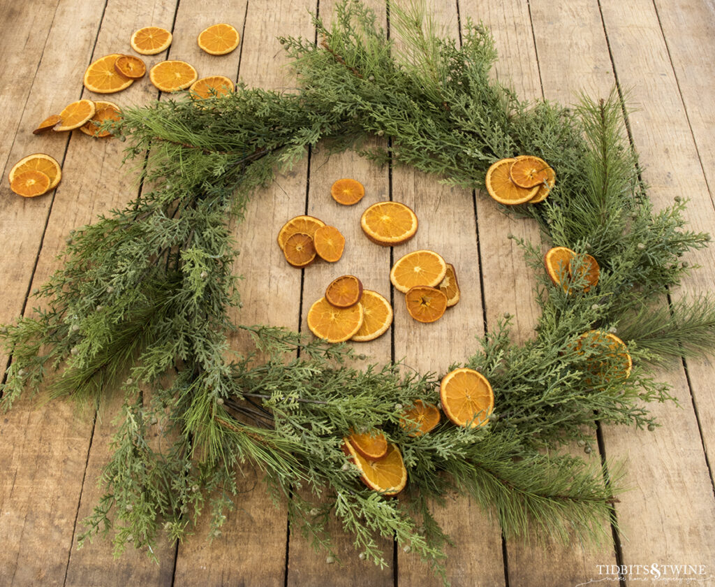 christmas greenery wired to wreath frame with dried oranges wired on