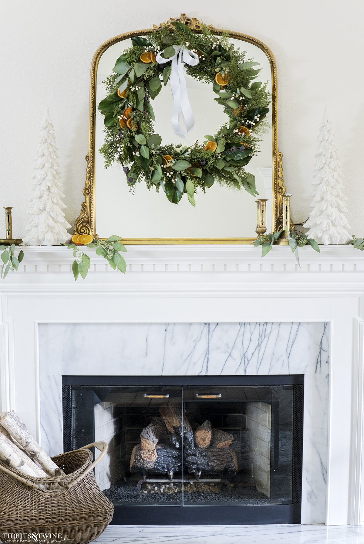 dried orange slice Christmas wreath with greenery and berries on a gold mantel above a fireplace