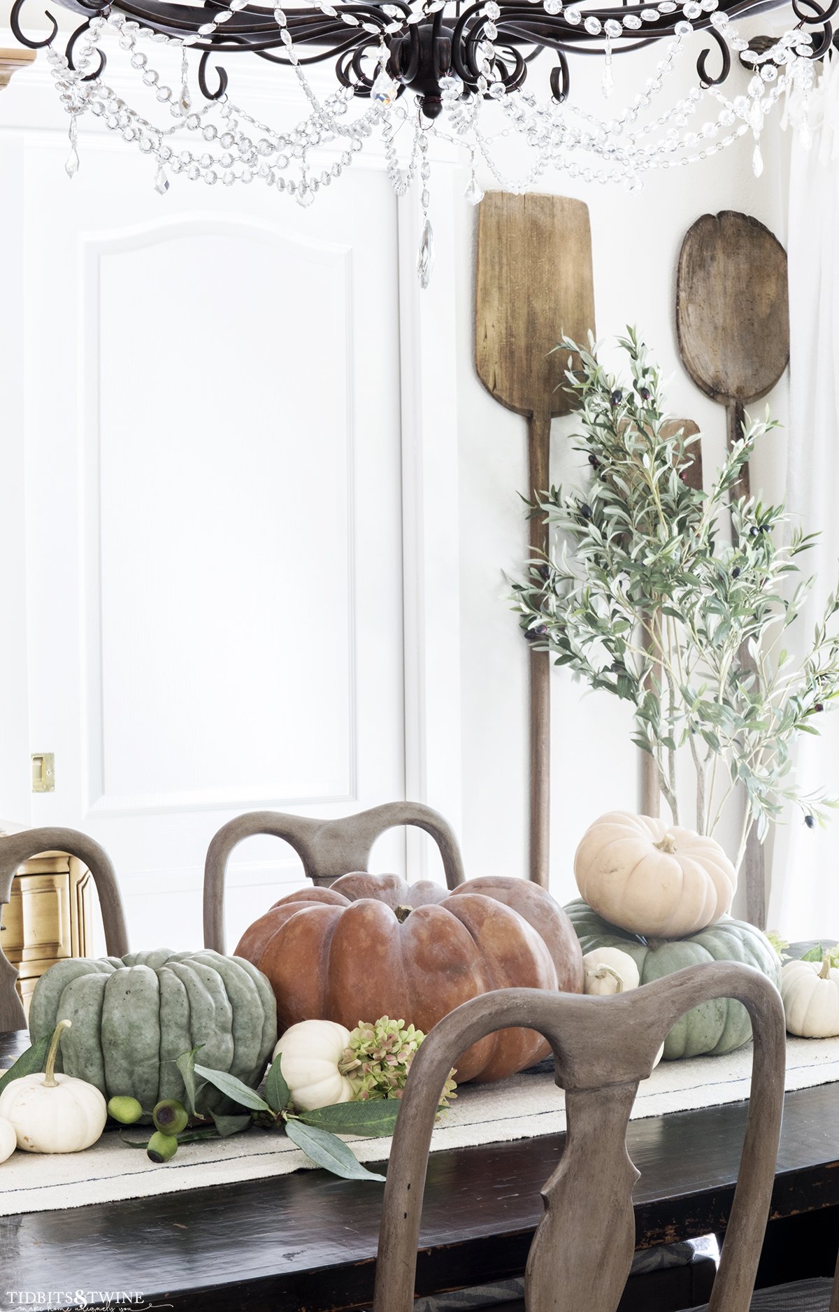 dining room with crystal chandelier and bread paddles on wall orange and green pumpkins down center of table