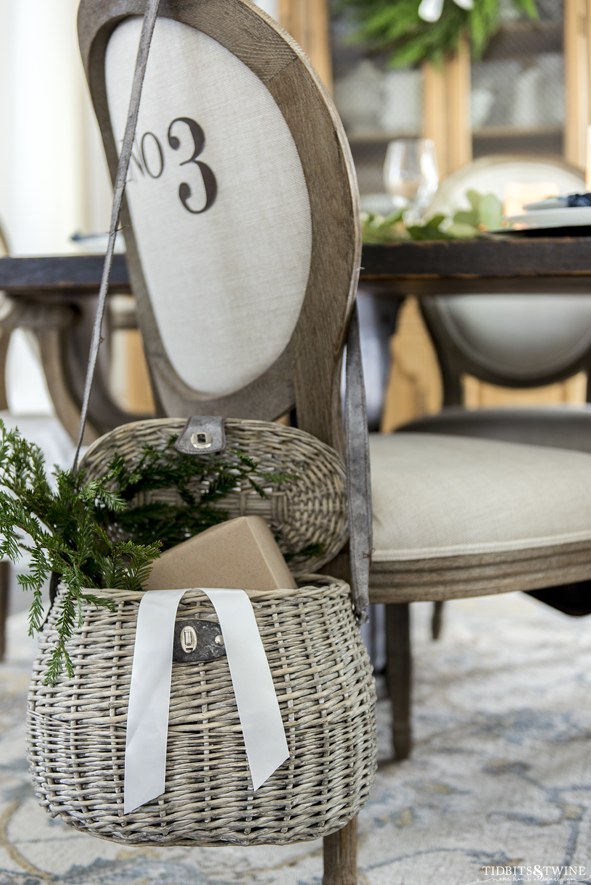 french numbered linen dining chair with fishing based over the back filled with greenery and Christmas presents