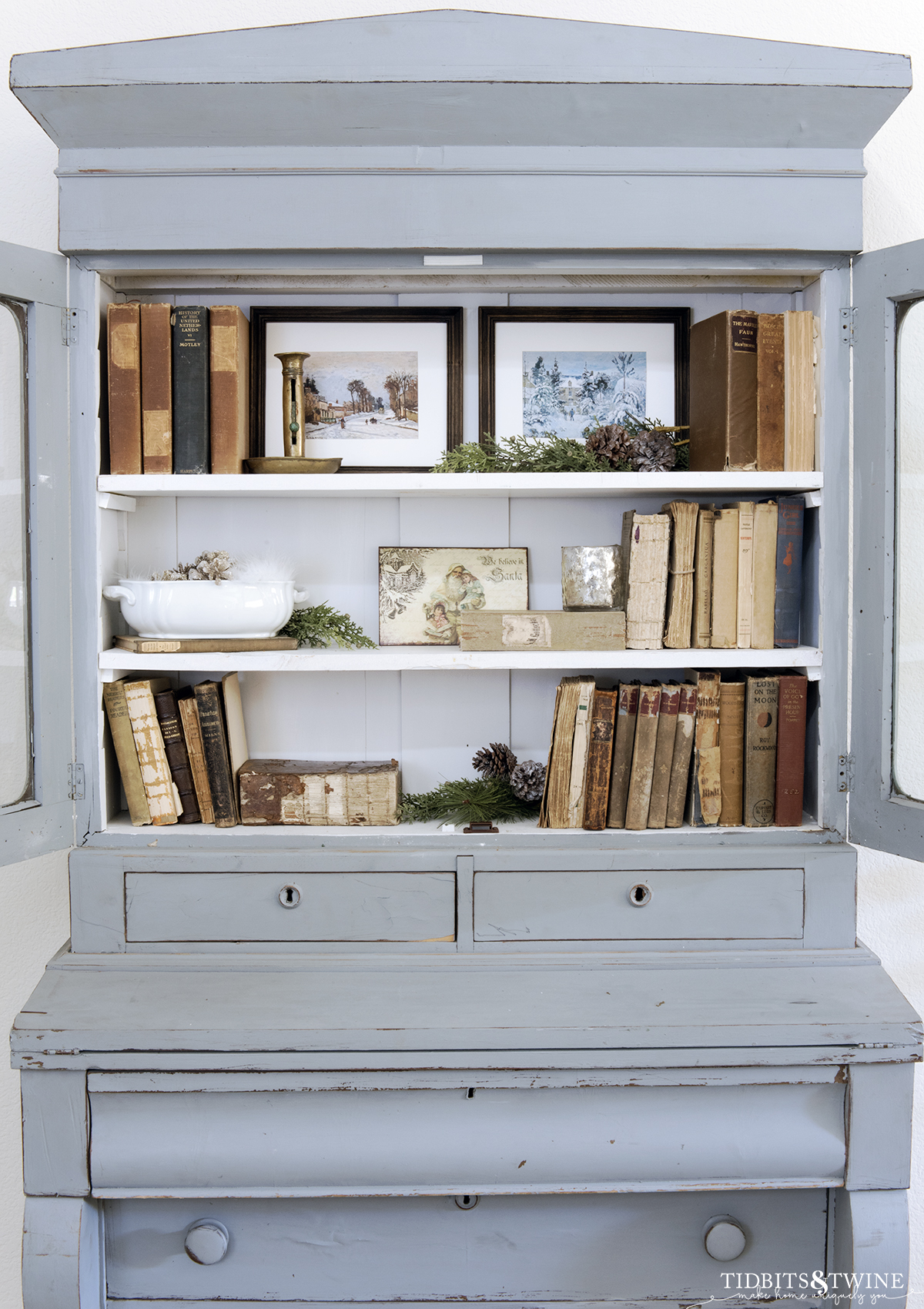 french blue cabinet with styled shelves holding antique books ironstone and greenery