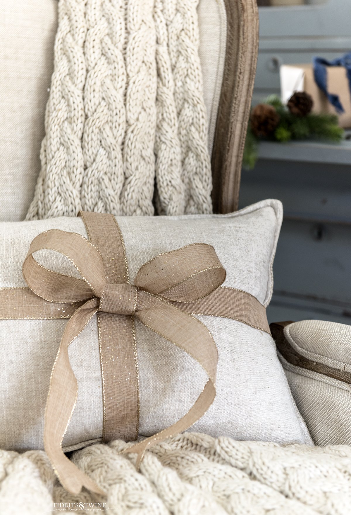 french beige linen wingback chair with pillow wrapped with a bow and chunky thrown behind the pillow