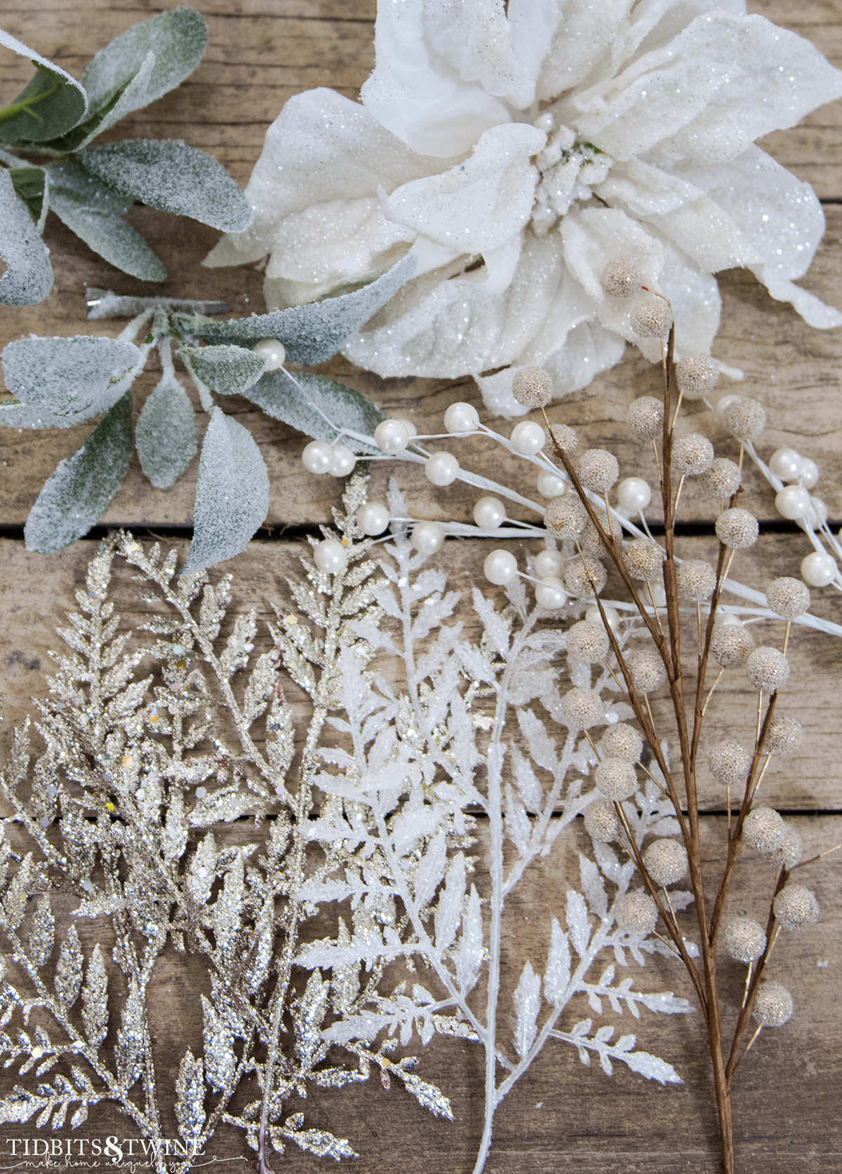 closeup of white poinsettia glitter ferns and glitter berries on a table