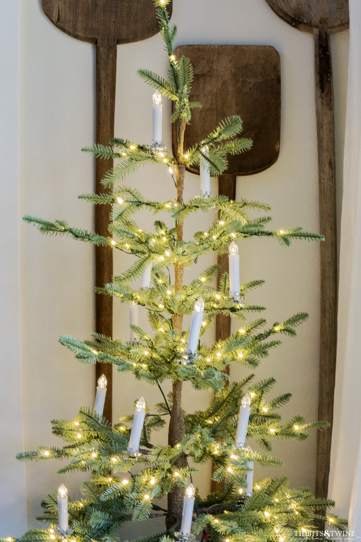 sparse christmas tree decorated with white clip on candles with diy metal bases in corner of dining room