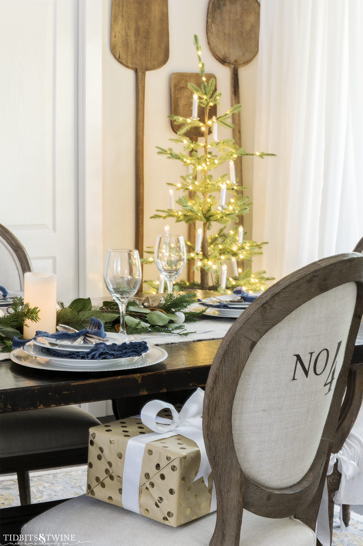 round french linen dining chair with blue and white place setting and christmas tree in corner