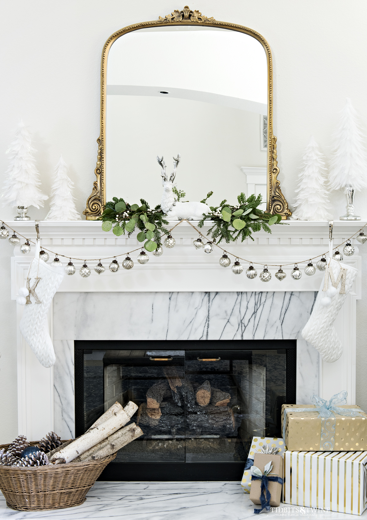 white fireplace with Carrera surround with mercury glass garland and gold french mirror above mantel