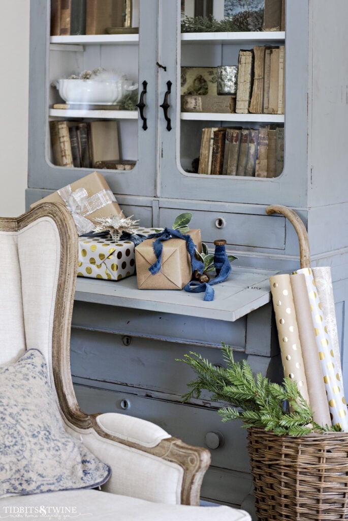 french blue secretary cabinet with presents on desk and wrapping paper in basket next to cabinet and french chair in front