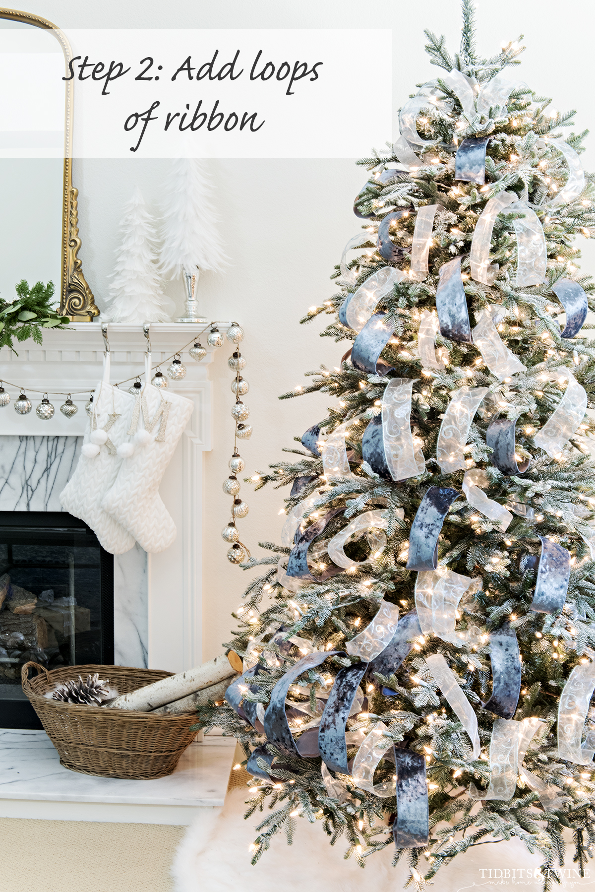 DIY flocked artificial christmas tree with three types of ribbon loops next to white fireplace with mercury garland and basket of wood
