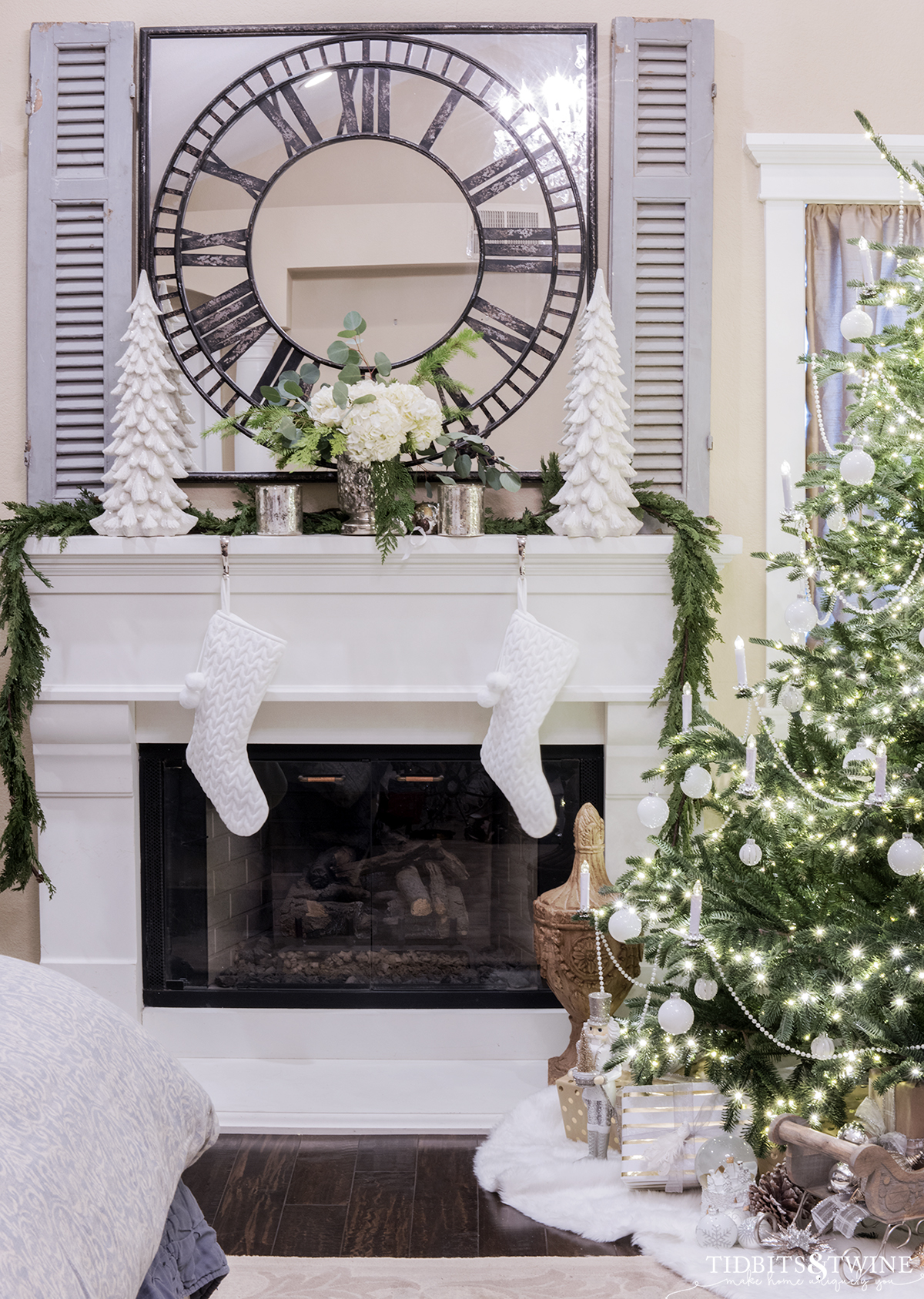 bedroom fireplace with mantel decorated for christmas with white trees greenery and hydrangeas and tree in the corner