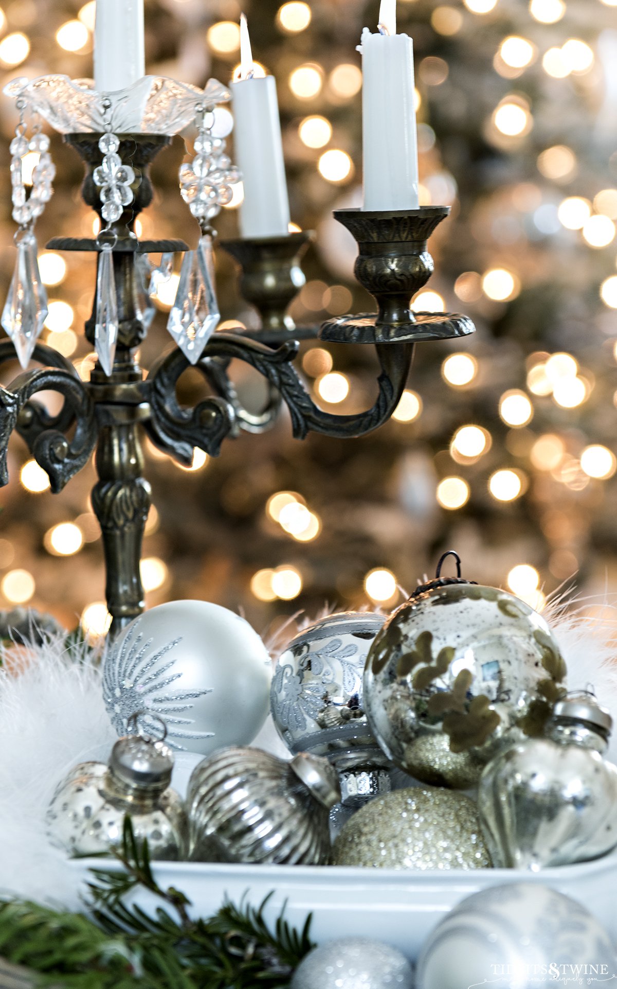 antique gold candelabra with ironstone bowl of silver and white christmas ornaments at the base