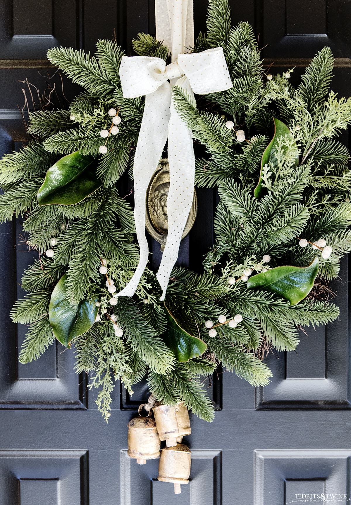black front door with brass lion door knocker and green christmas wreath on door with a polka dot bow
