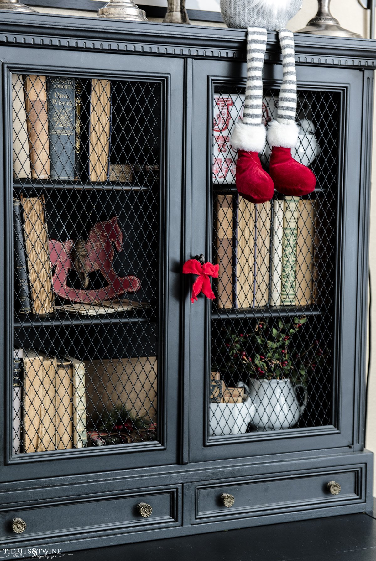 bedroom with black French secretary hutch decorated for christmas with red ribbons and greenery