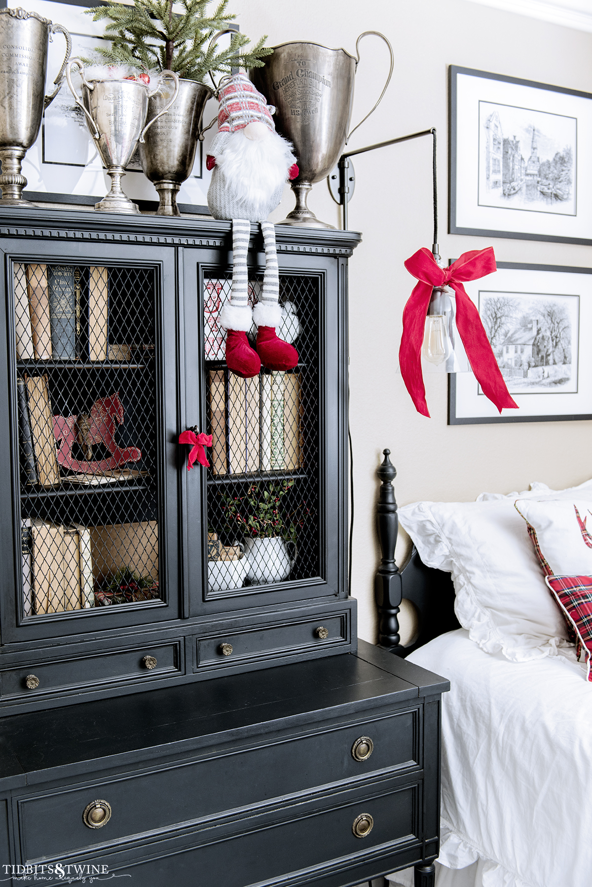 bedroom with black black French secretary hutch on side of twin bed decorated for christmas with red ribbons and greenery