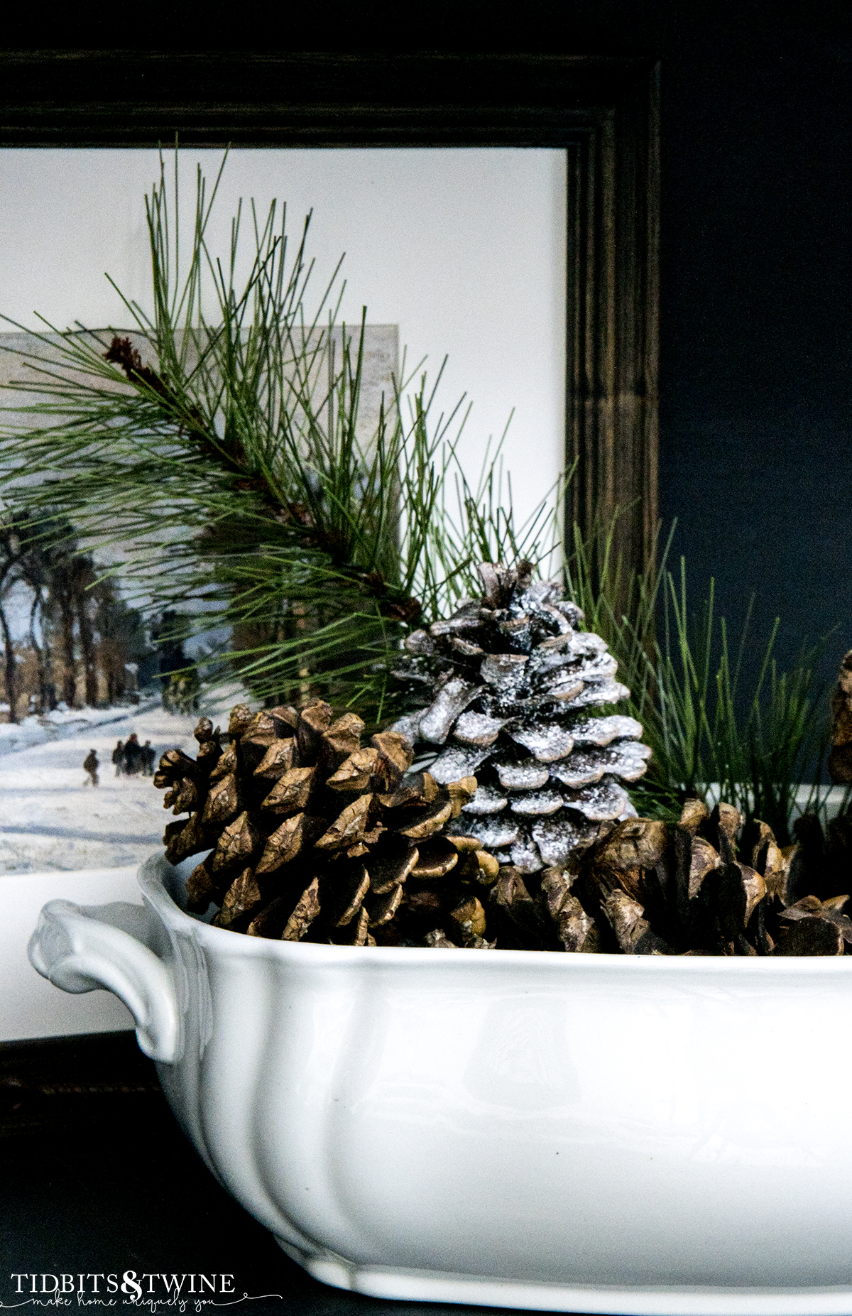 closeup of white ironstone tureen filled with pinecones and an evergreen branch for winter