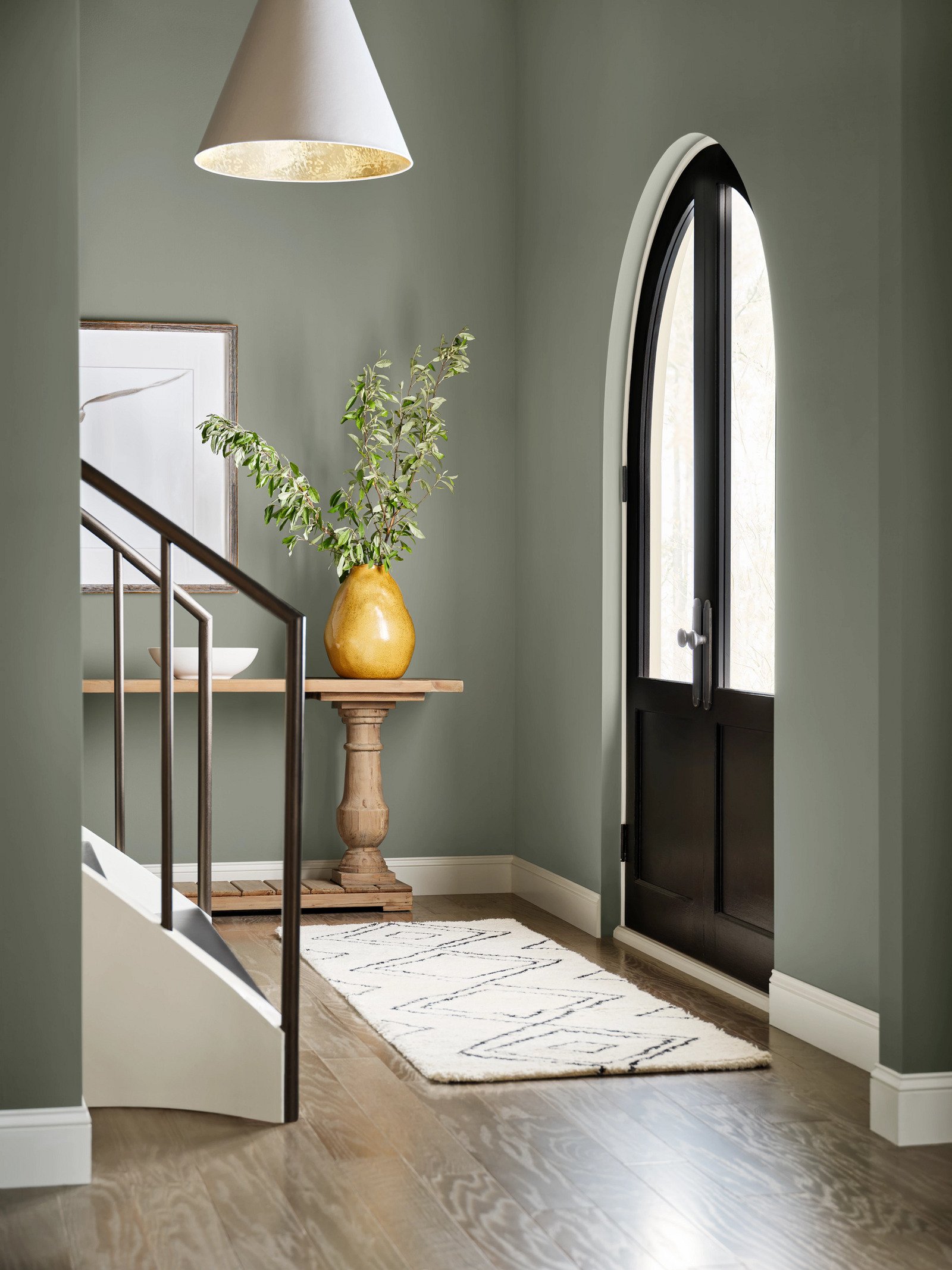 sherwin williams evergreen fog color of the year painted in a foyer with wood floors and black front door