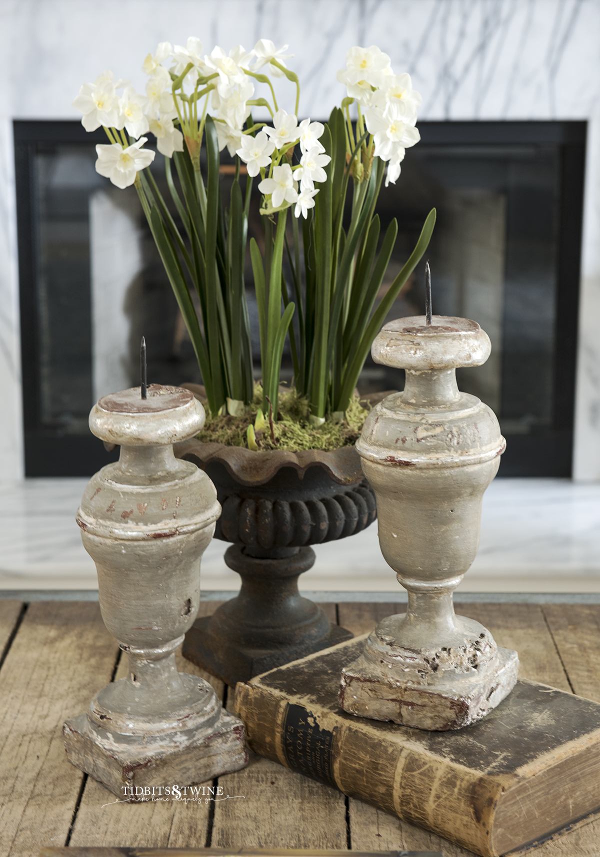 faux paperwhites in old french urn on coffee table next to french candle sticks and old books