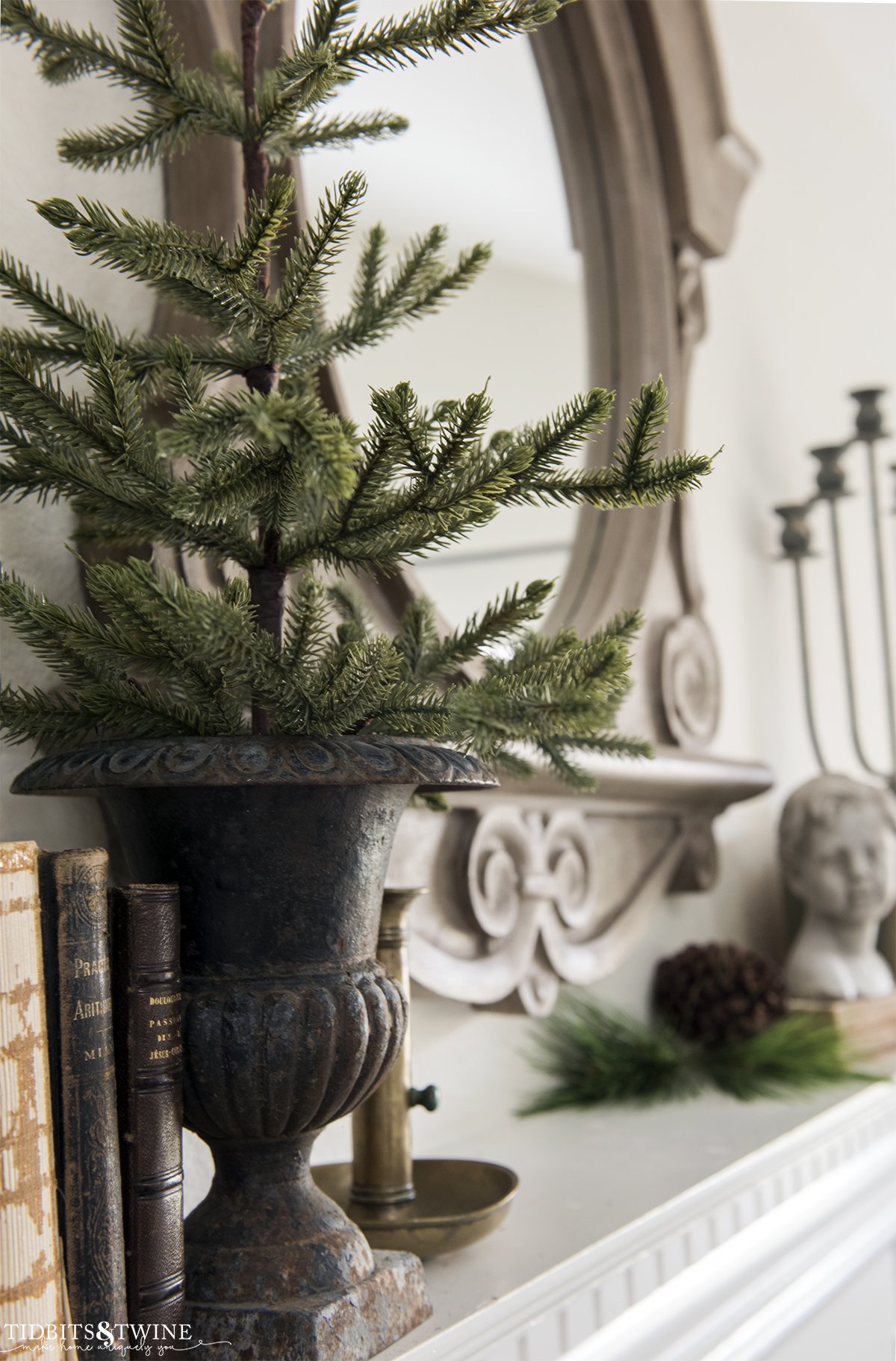 small evergreen tree in french urn on fireplace mantel decorated for winter