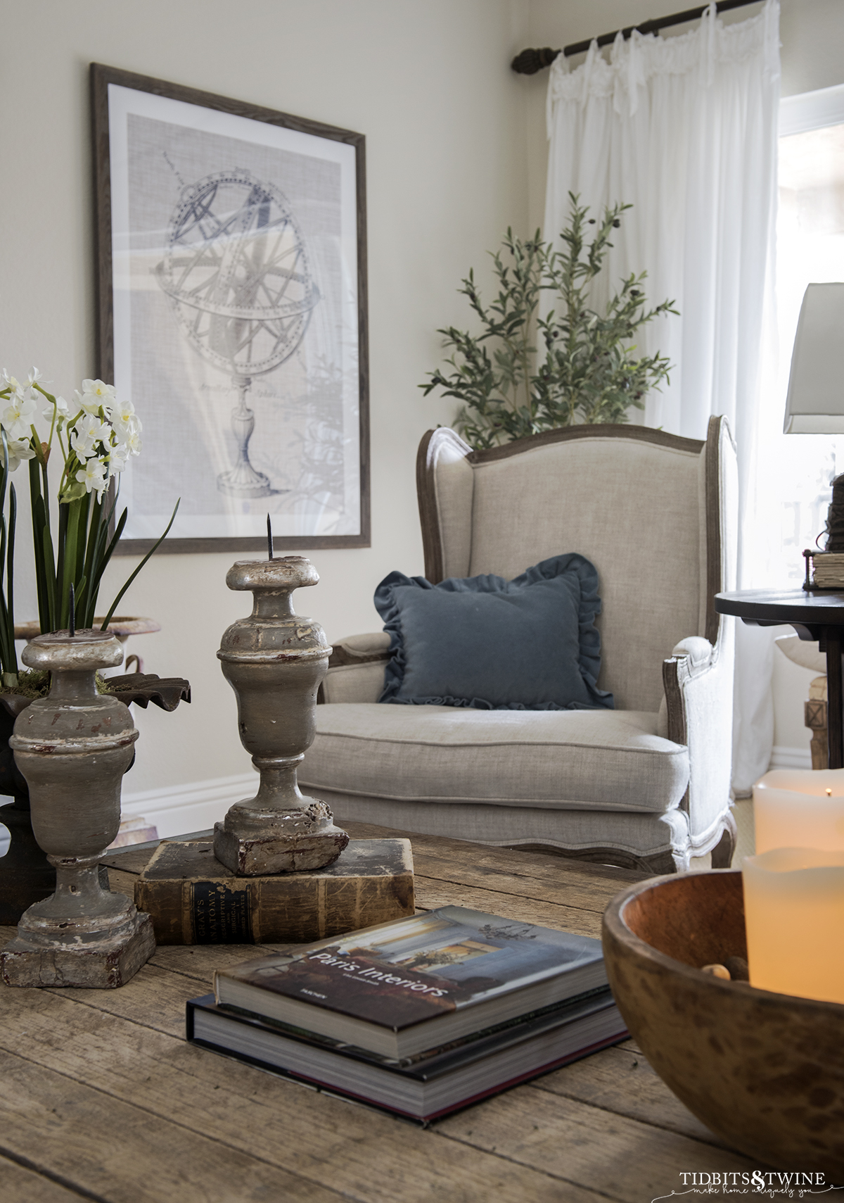 French living room with linen wingback chairs and coffee table styled with books candles and paperwhites for Winter