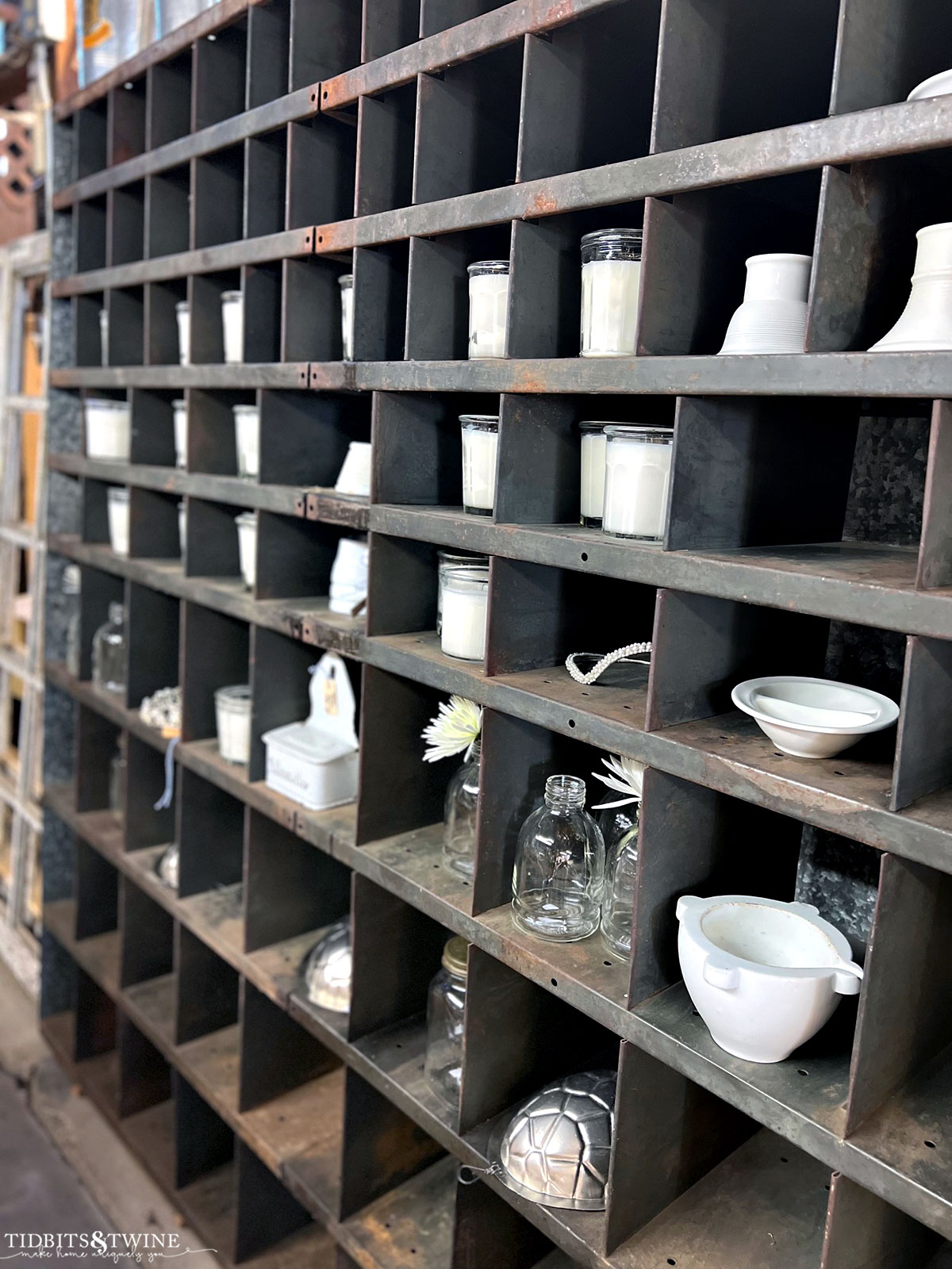 large metal cubby filled with white candles and white ironstone