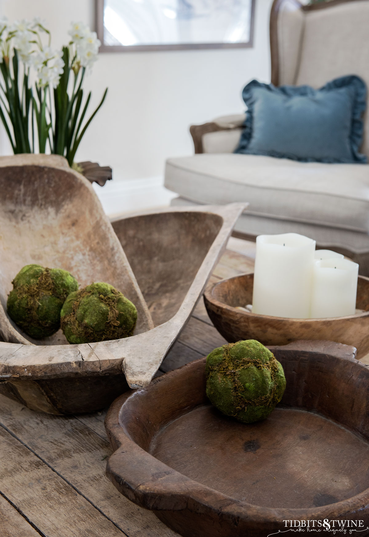 four dough bowls on a coffee table two oval and two round with moss balls and candles