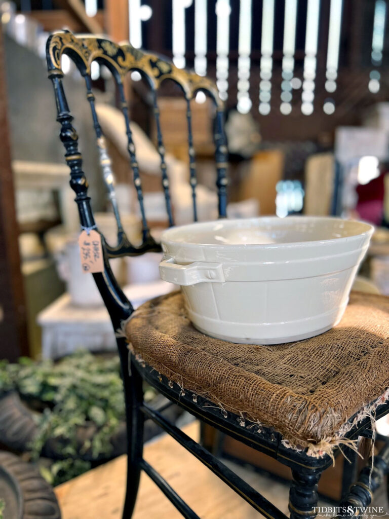 small black antique chair with burlap seat and white bowl sitting on seat