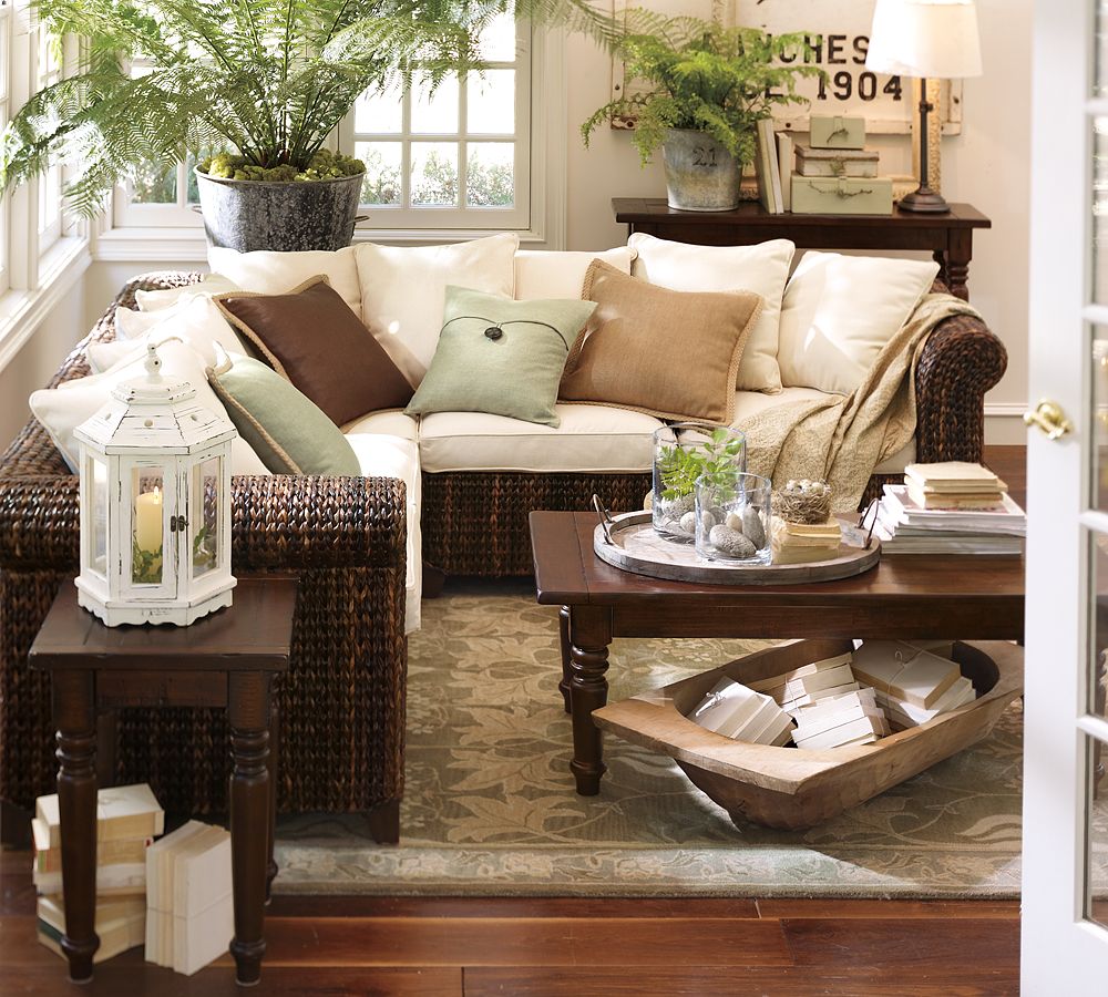 living room with wicker sofa sectional with large ferns around and large dough bowl under coffee table full of books