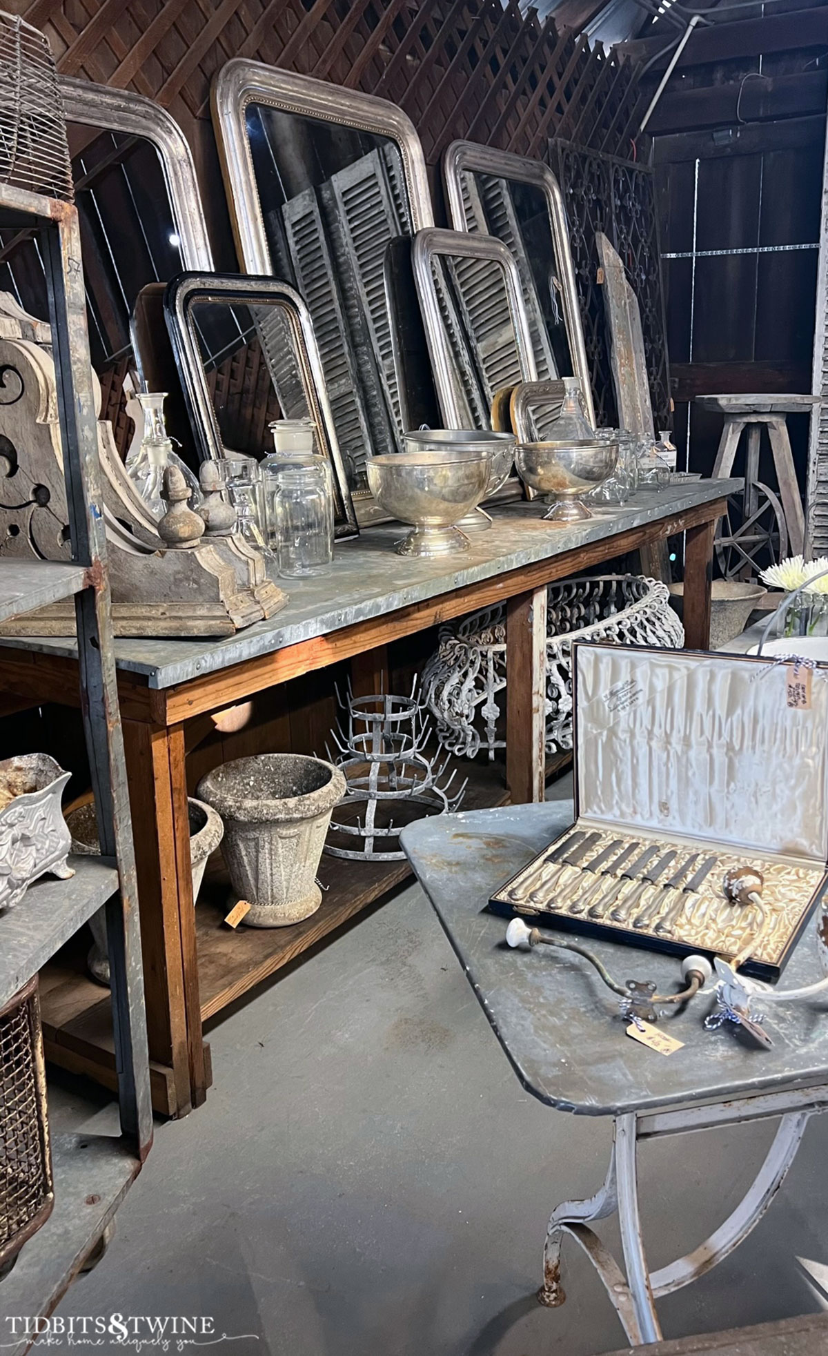 industrial table full of silver antique mirrors and silver champagne bowls and jardiniers