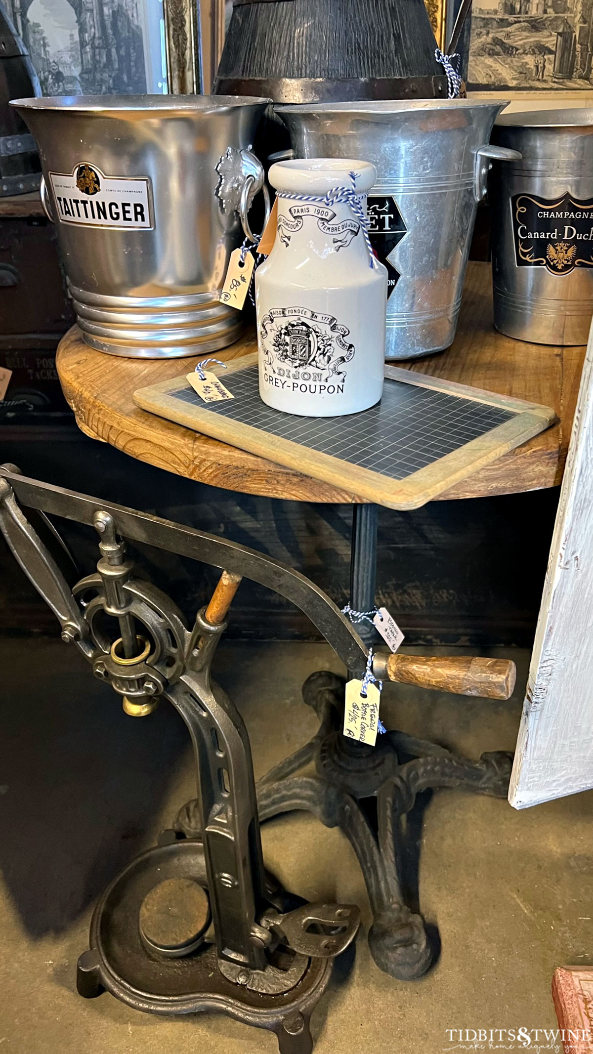 antique bistro table with champagne buckets on top and a grey poupon jar