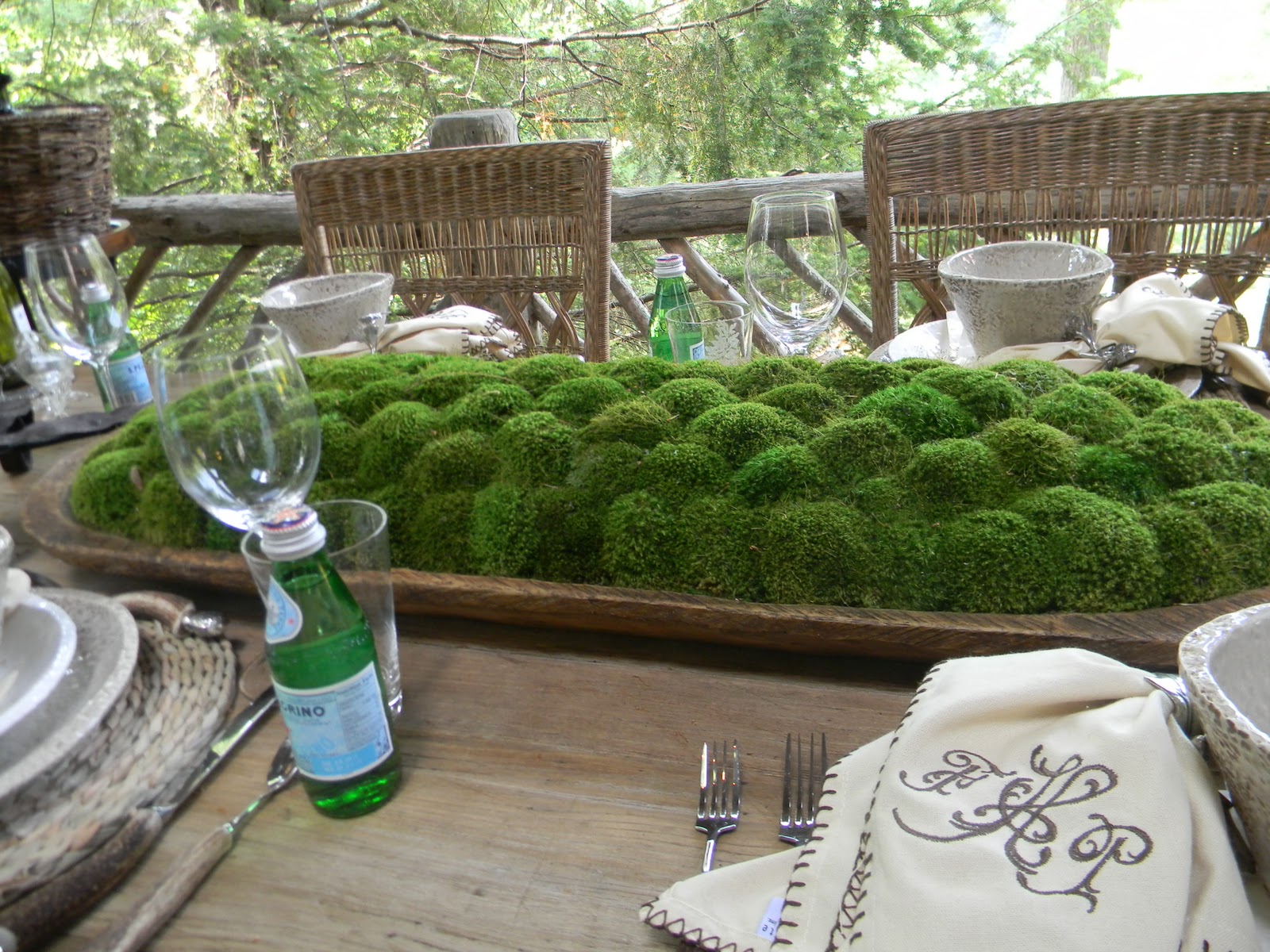 outdoor table on a porch with large dough bowl filled with moss as the centerpiece