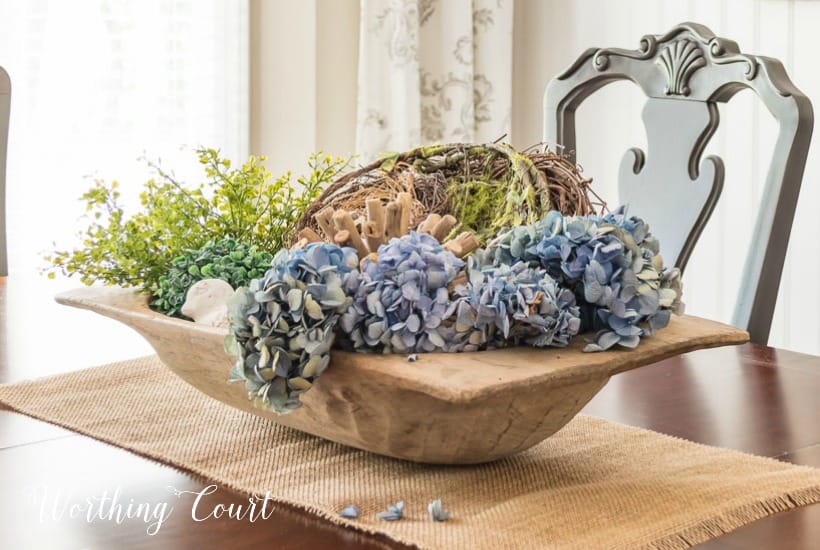 dough bowl on dining table with blue dried hydrangea moss and greenery