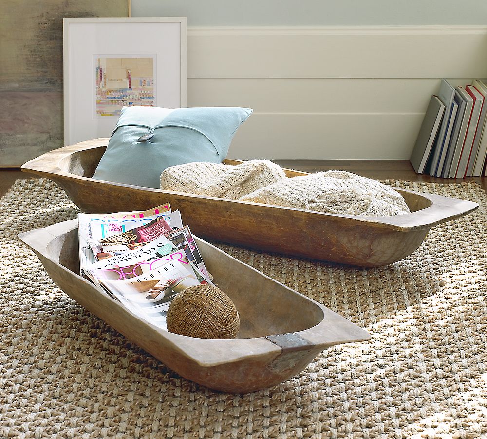 two large antique dough bowls on the floor one with magazines and one with beige throw and turquoise pillow