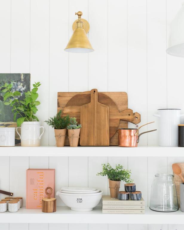 white kitchen with vertical planted walls and white shelves decorated with bread boards copper and plants