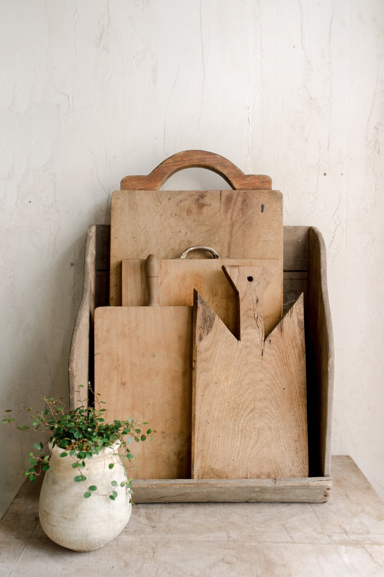 french bread boards stacked vertically on a table next to a small plant