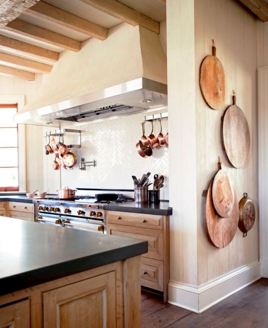 kitchen with black countertops and copper pots hanging by stove and bread board display hanging on wall