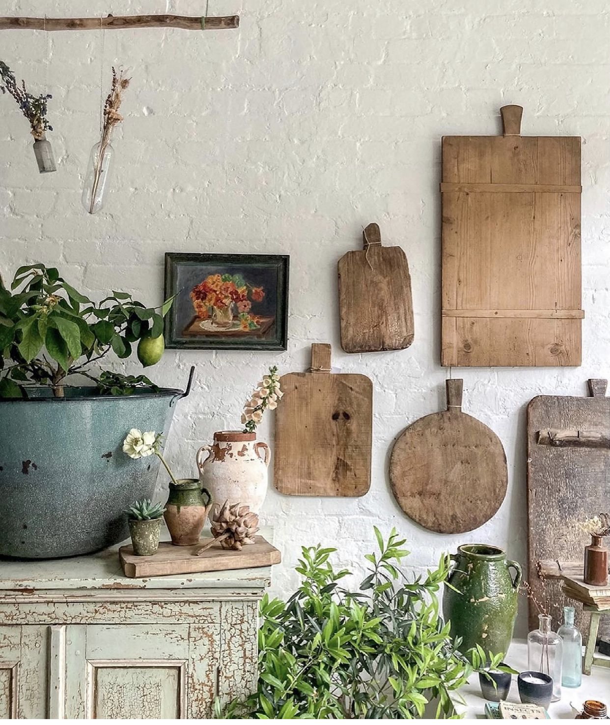 white brick wall with antique bread boards hanging as a display with vintage bottles on table