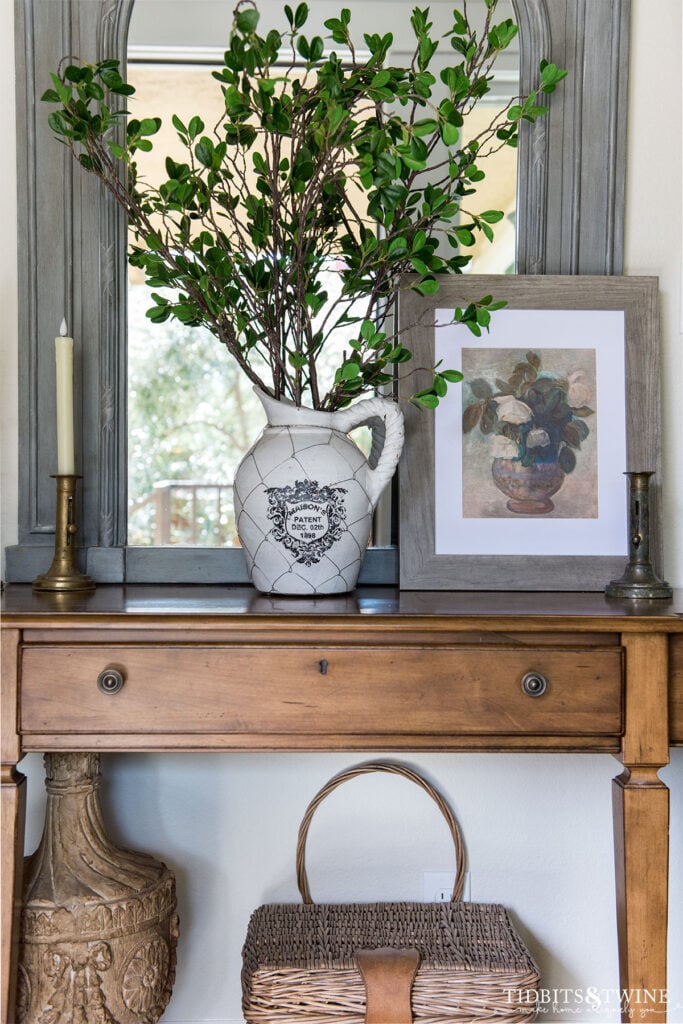 Entryway with blue french mirror and small table decorated for Spring with vase of branches